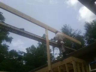 Carpenter setting a ridge beam over a new addition frame — Ice Dam Removal by Roofing Brothers in Suffolk