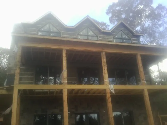 Dormers and porch framing on a large log home under construction — Roof Coating work by our crew in Suffolk