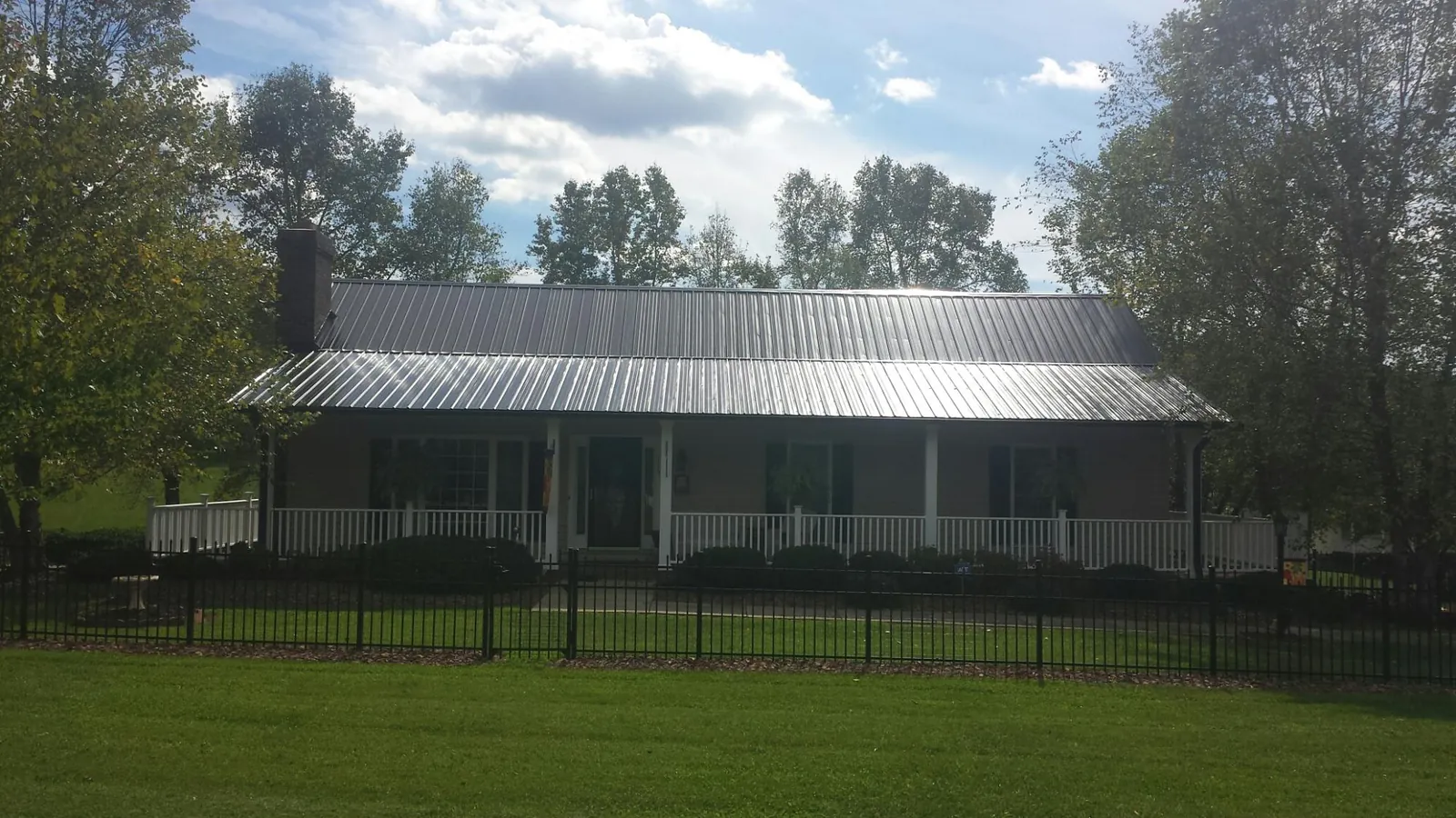 Gray metal roof on a brick ranch with a full width front porch — Gutter Guard Installation work by our crew in Suffolk