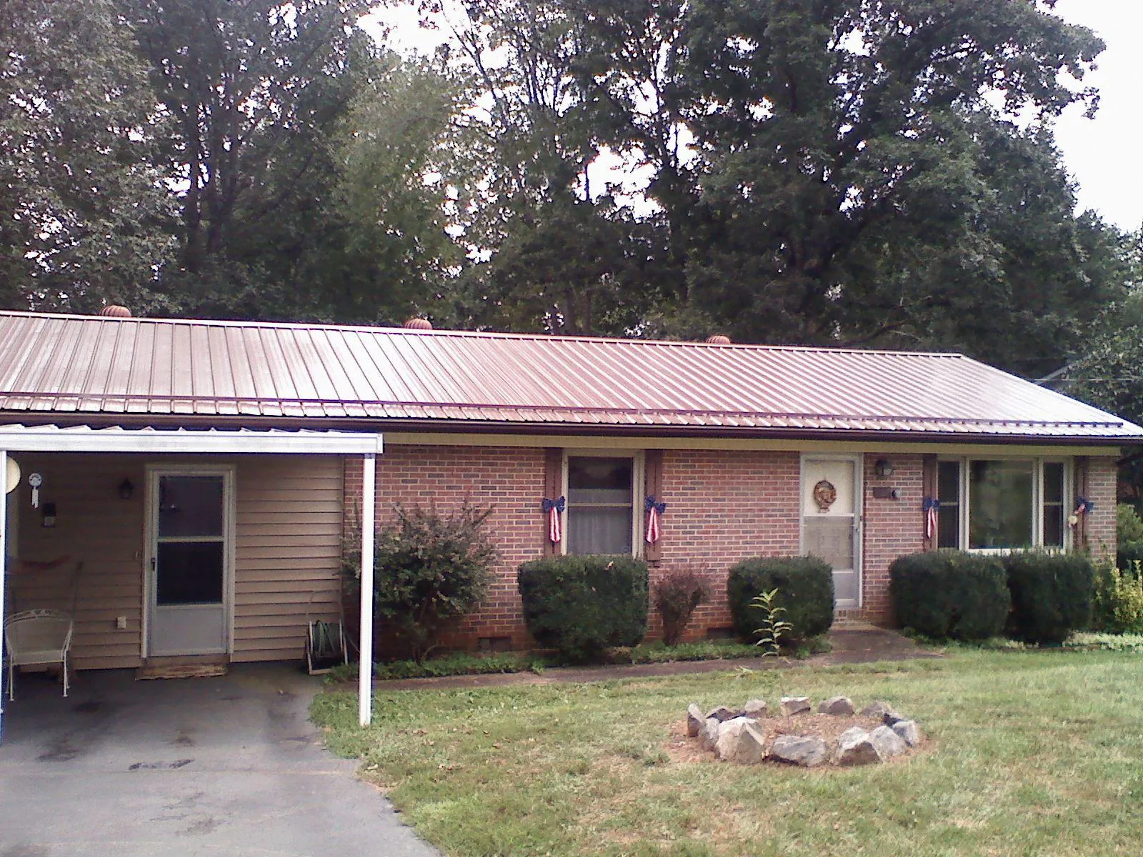 Bronze metal roof and carport on a brick ranch home — Roof Repair work by our crew in Suffolk